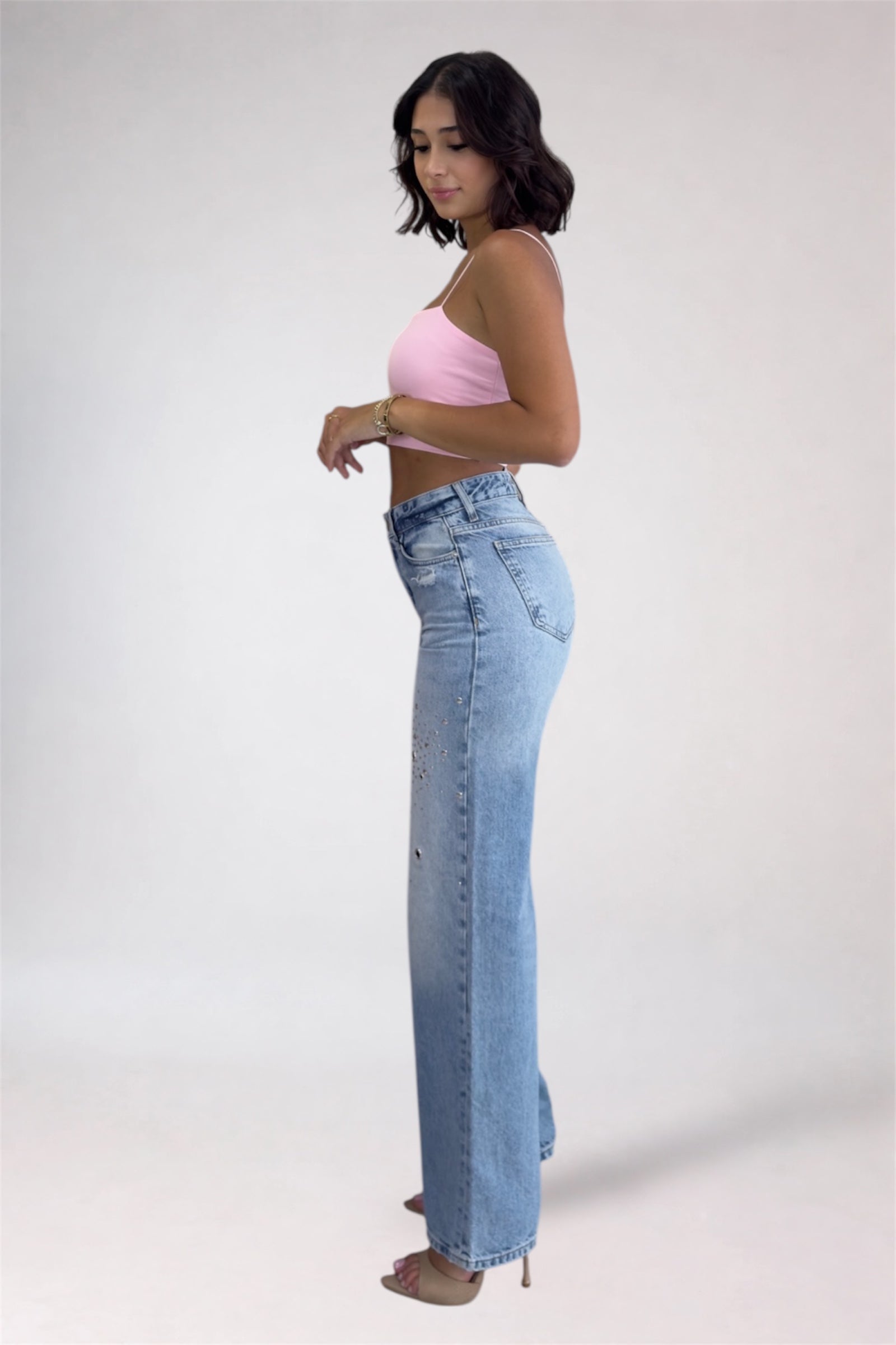 Woman wearing a pink top and light blue jeans on a white background