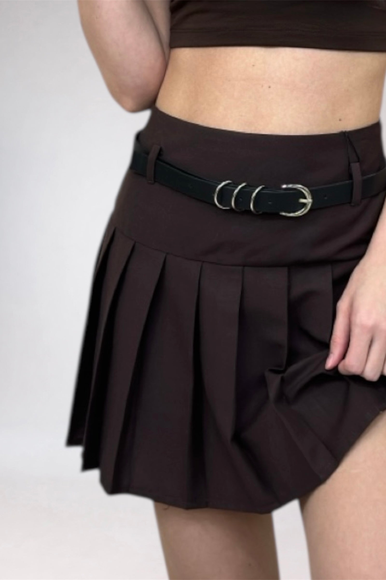 Brown pleated skirt with a black belt on a white background