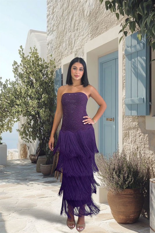 Woman in a purple dress standing in front of a stone building with a blue door.