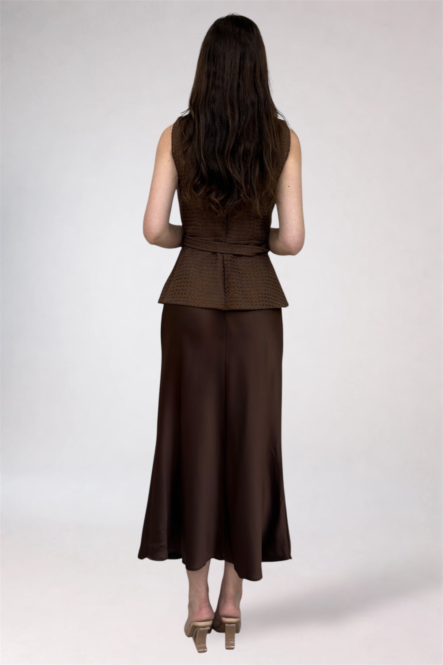 Woman wearing a brown peplum top and wide-leg pants on a white background