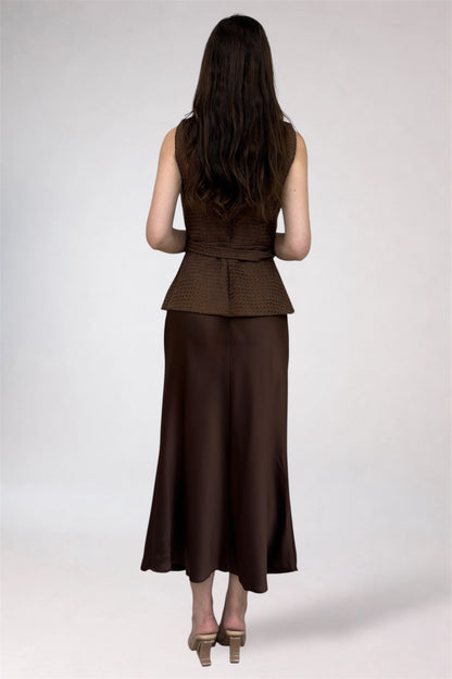 Woman wearing a brown peplum top and wide-leg pants on a white background