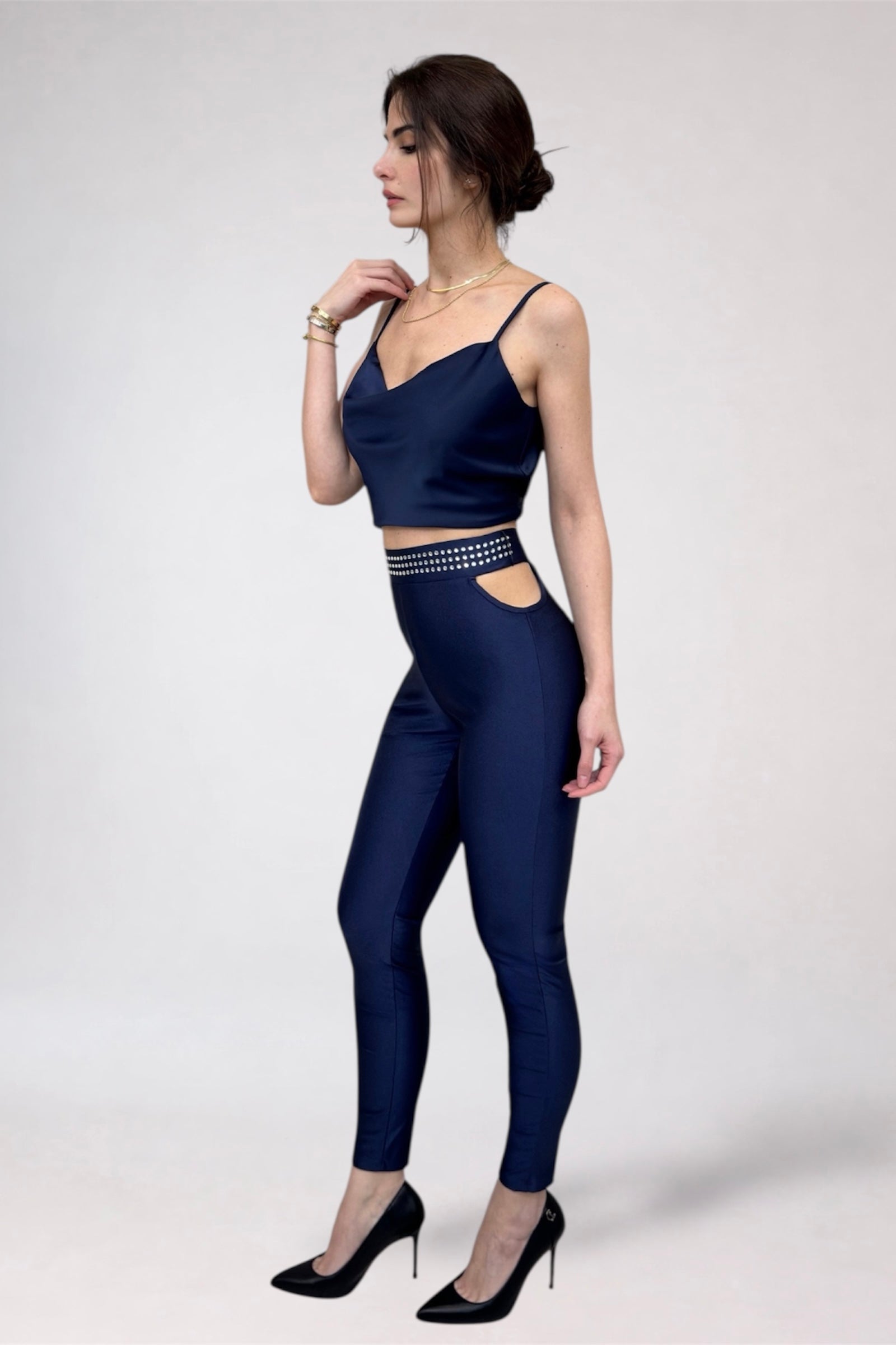 Woman wearing a navy blue outfit with cut-out details on a white background