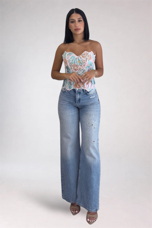 Woman wearing a floral top and blue jeans on a white background
