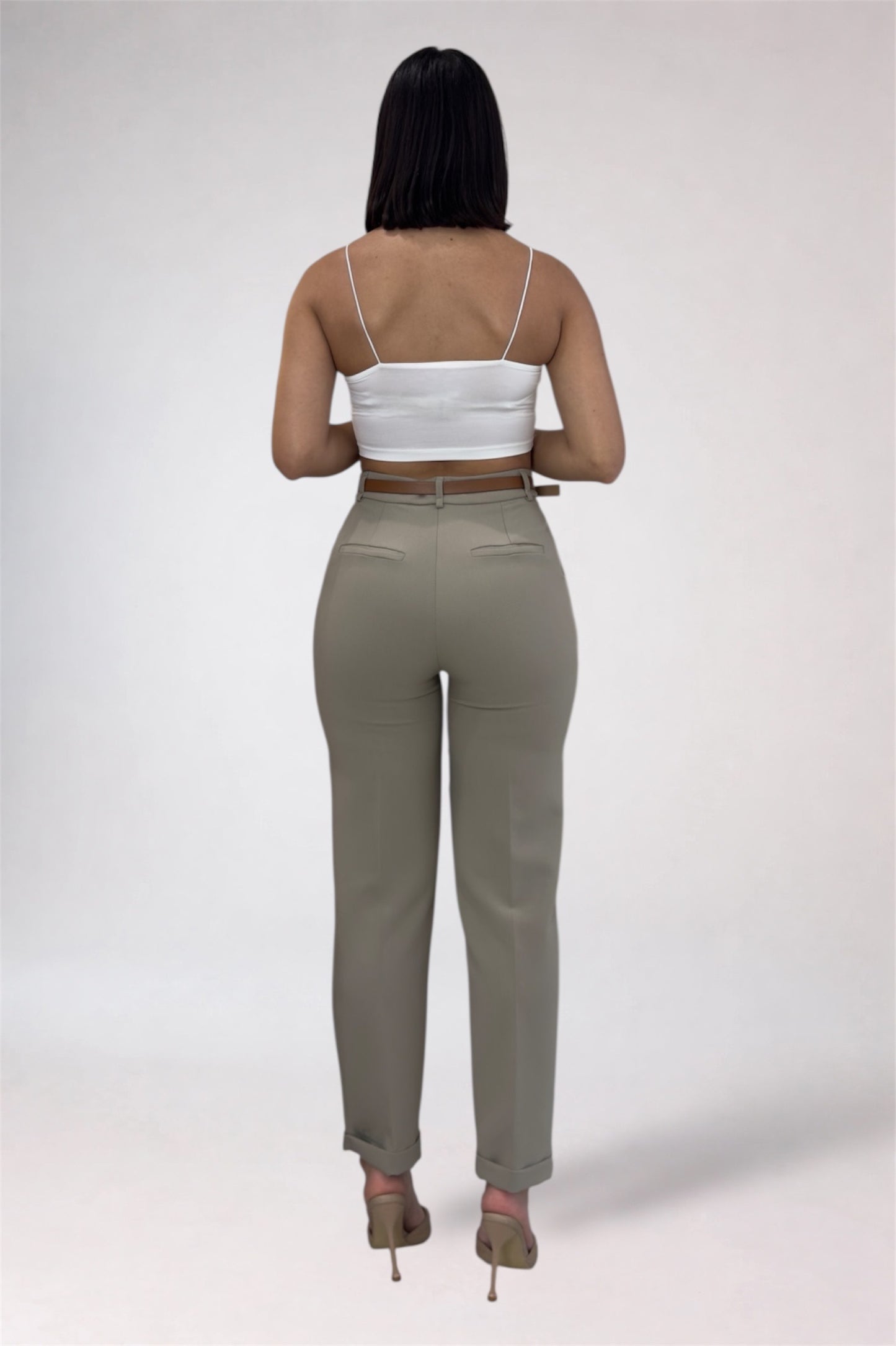Woman wearing a white top and beige pants on a plain background