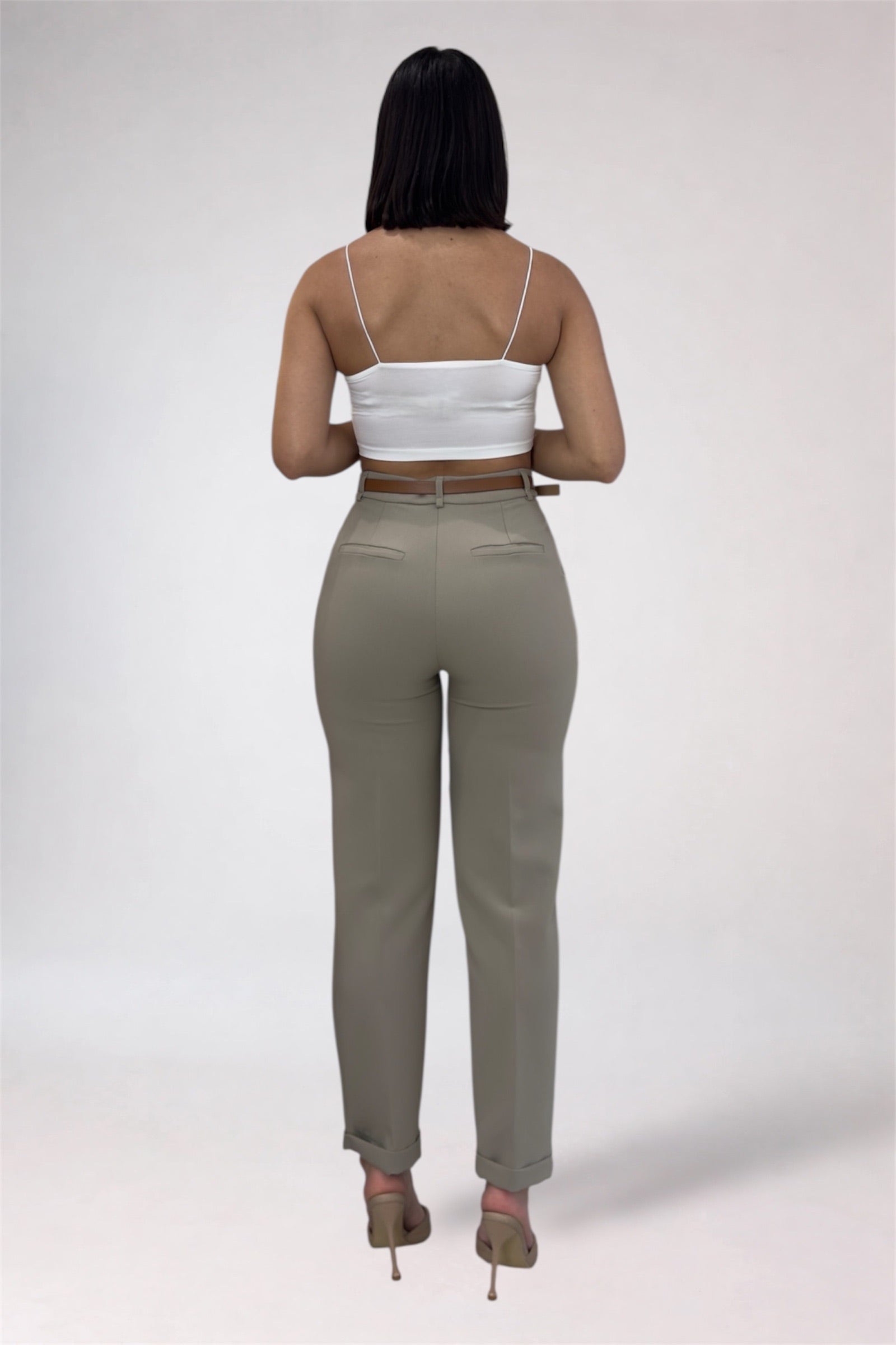 Woman wearing a white top and beige pants on a plain background