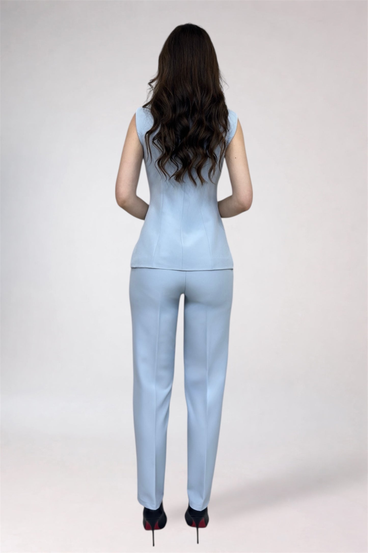 Woman wearing a light blue jumpsuit on a white background