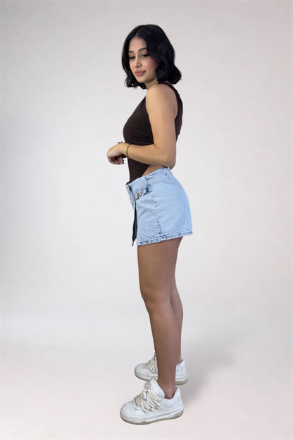 Woman wearing a black sleeveless top and light blue denim shorts on a white background