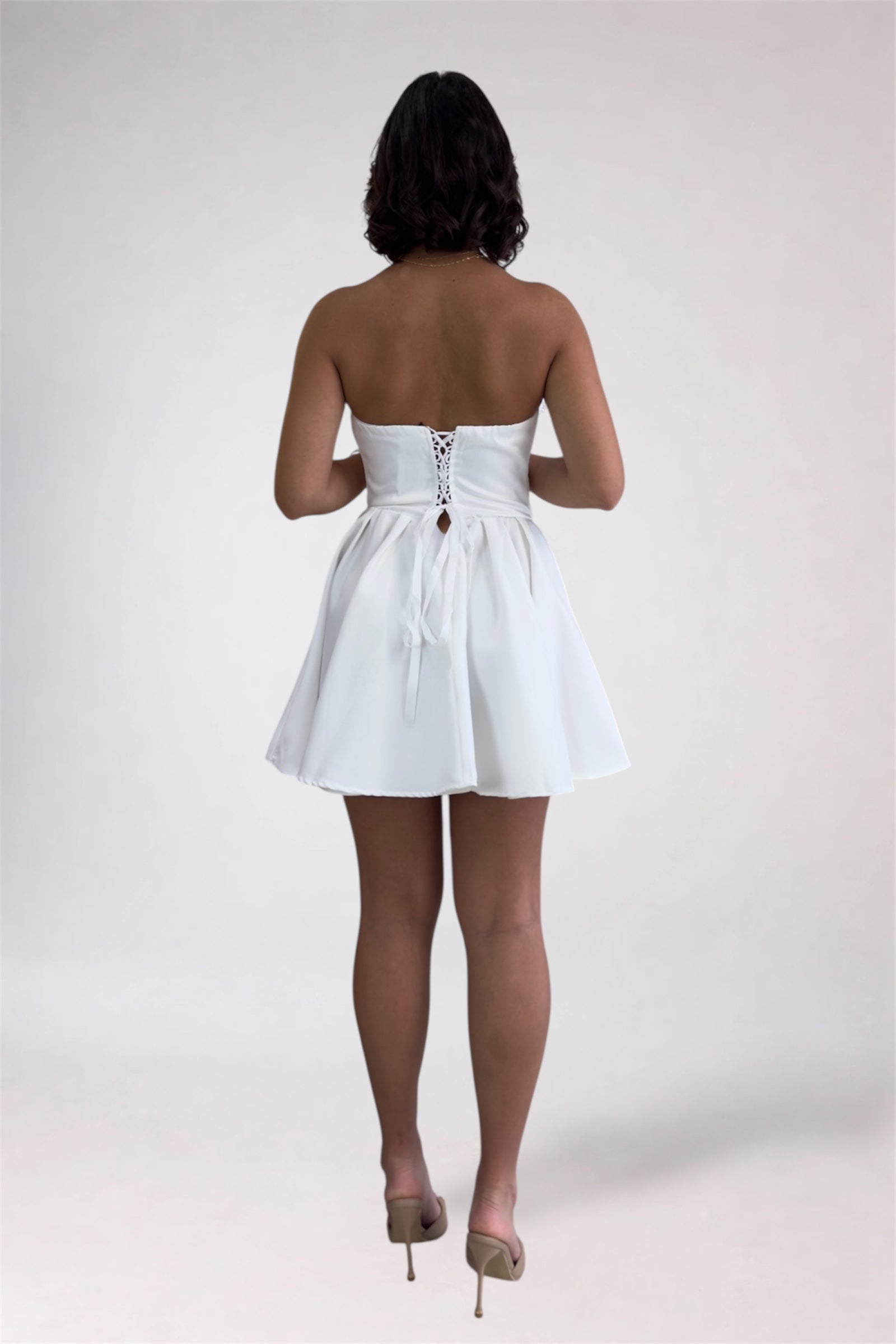 Woman wearing a white strapless dress on a plain background