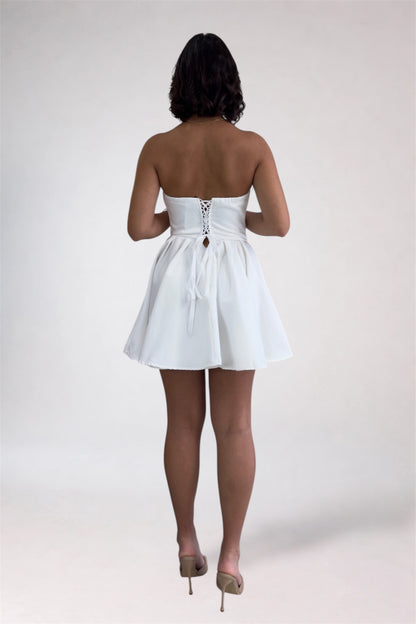 Woman wearing a white strapless dress on a plain background