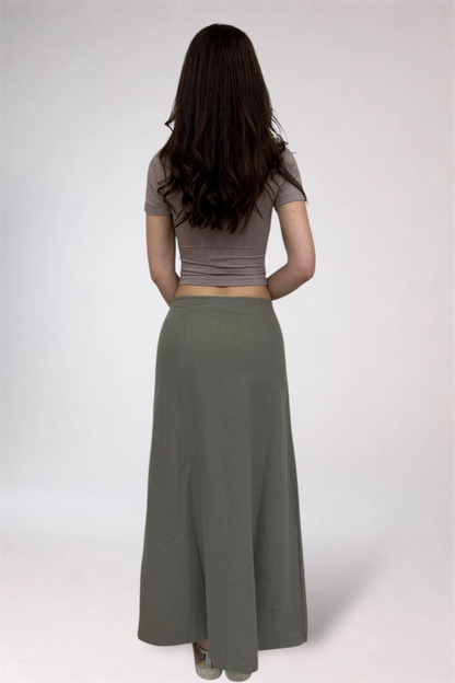 Woman wearing a brown crop top and long gray skirt on a white background