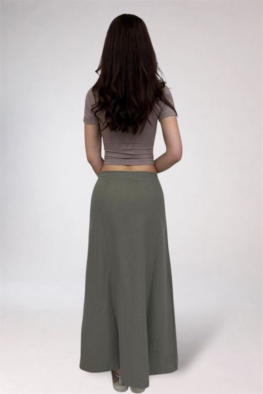 Woman wearing a brown crop top and long gray skirt on a white background