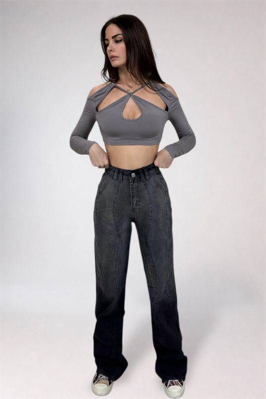 Woman wearing a gray long-sleeve crop top and black high-waisted jeans on a white background