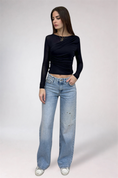 Woman wearing a black long-sleeve top and light blue jeans on a white background