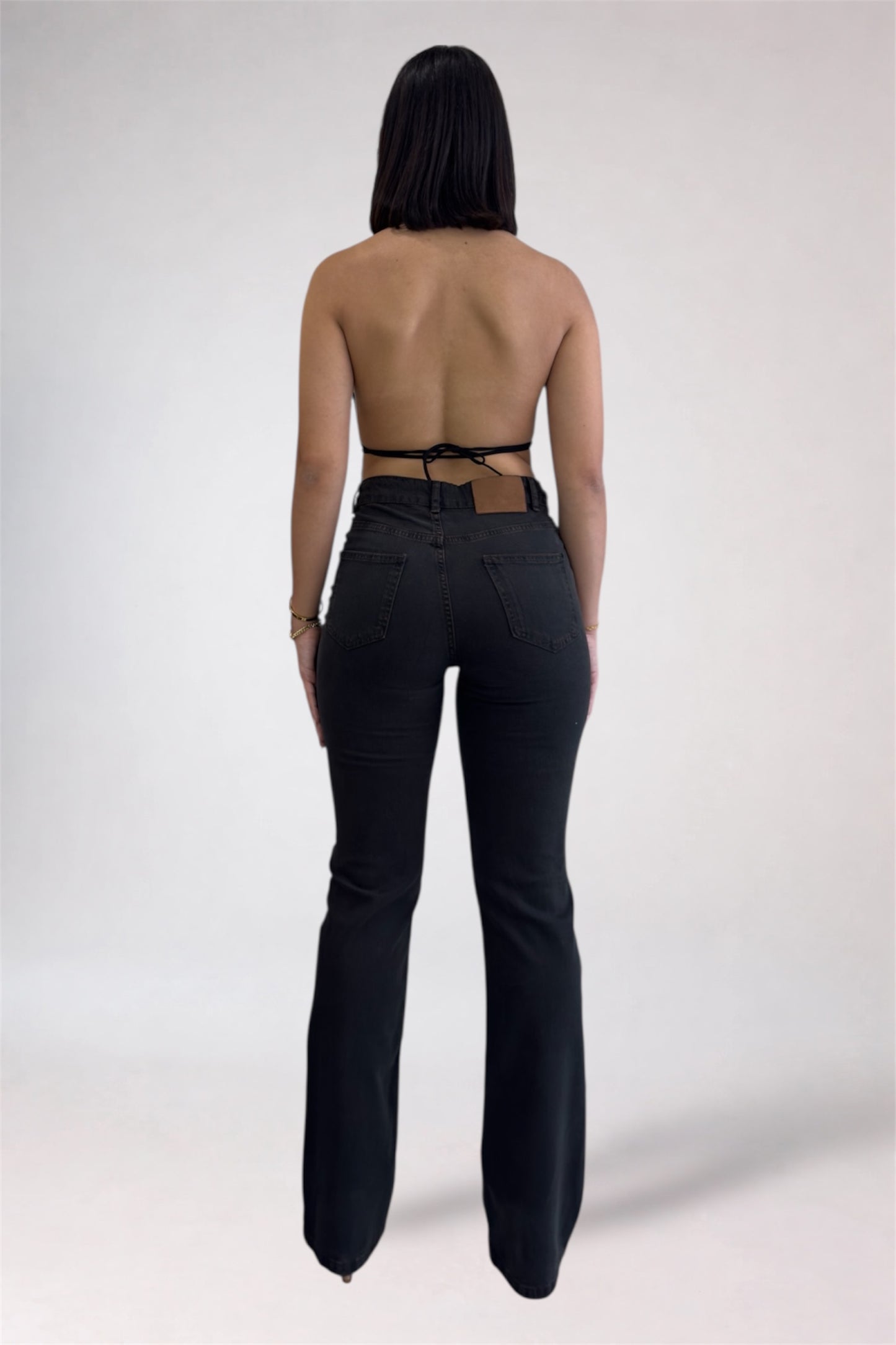 Person wearing black high-waisted pants with a strapless top on a white background