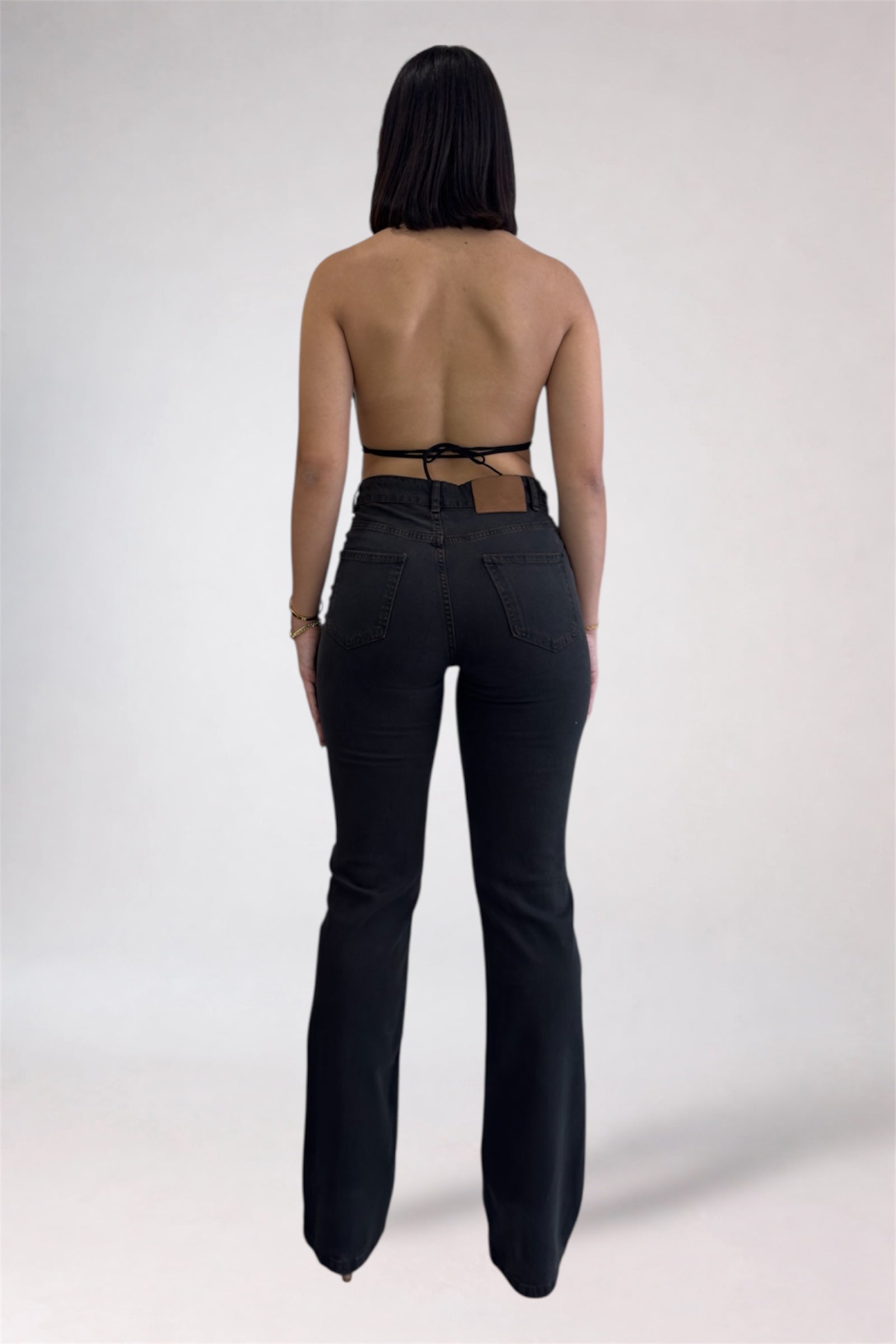 Person wearing black high-waisted pants with a strapless top on a white background