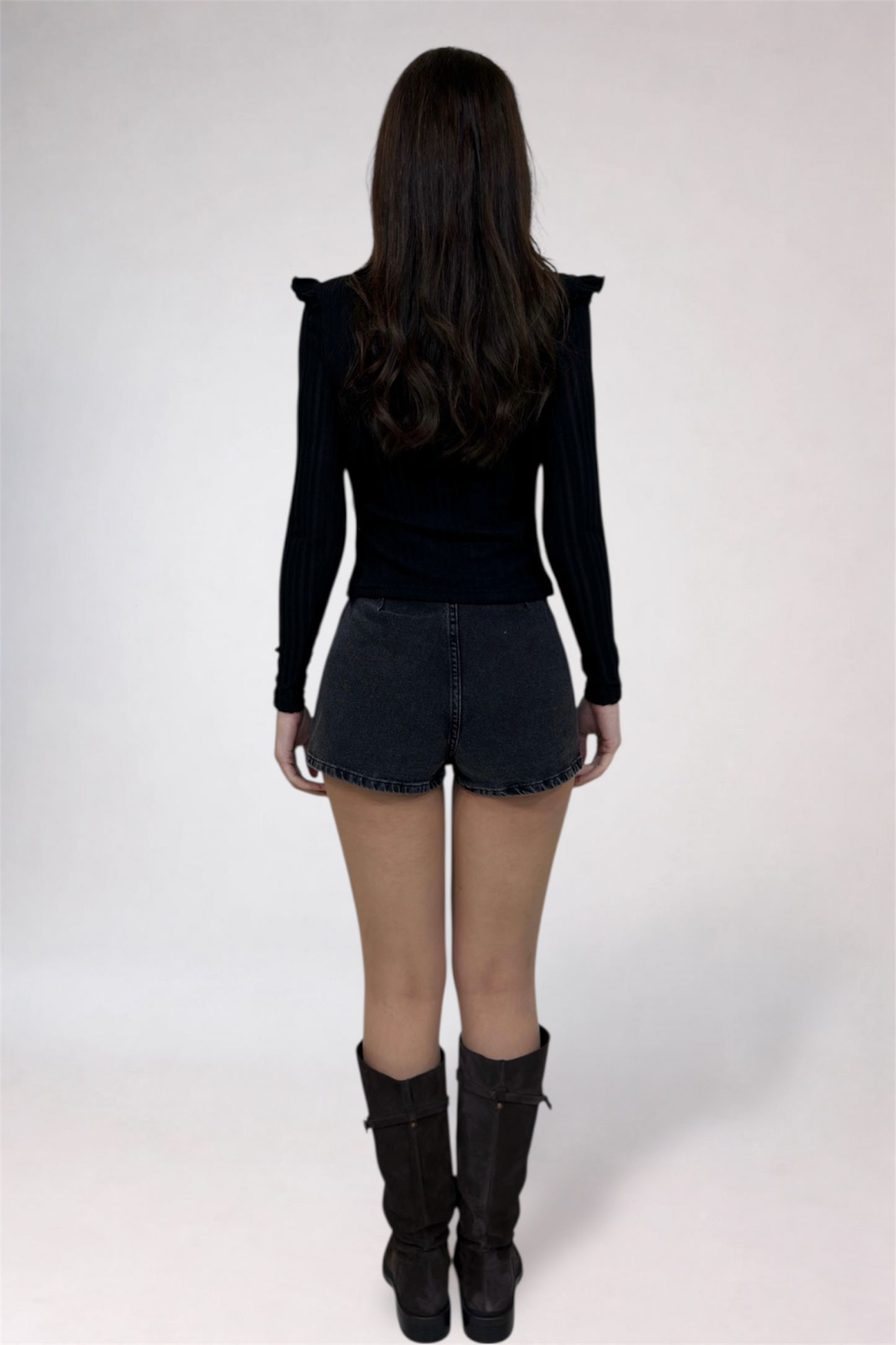 Person wearing a black outfit with shorts and boots on a white background