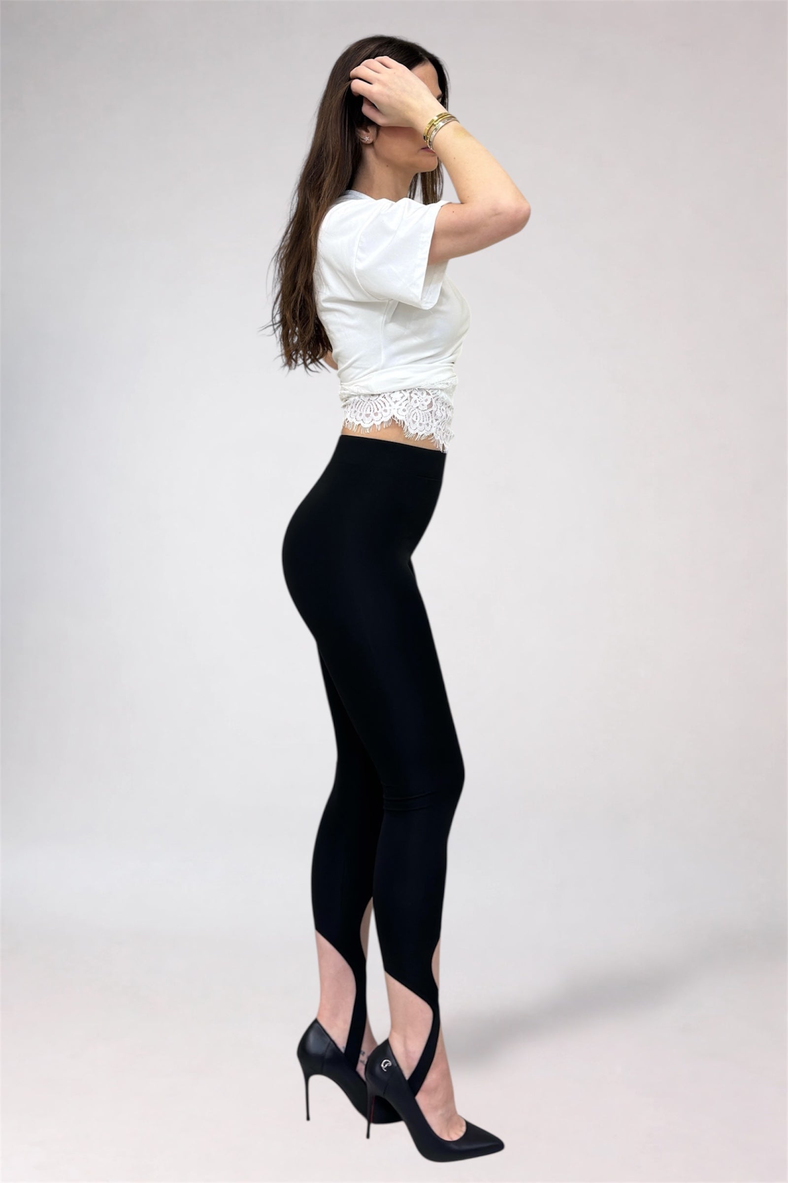 Woman wearing a white top and black leggings on a plain background