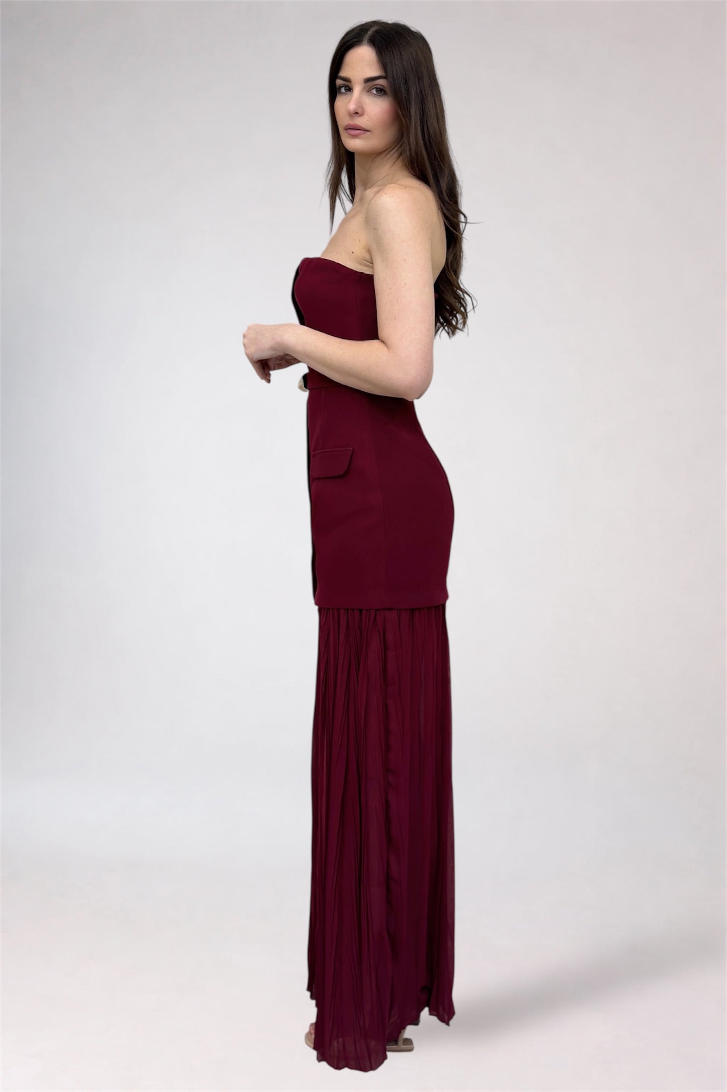 Woman wearing a burgundy strapless gown on a white background