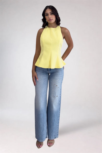 Woman wearing a yellow sleeveless top and blue jeans on a white background