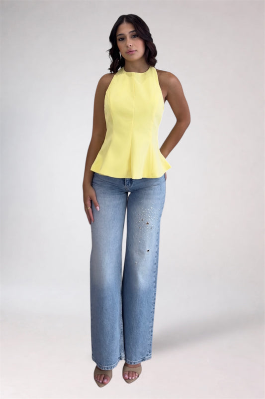 Woman wearing a yellow sleeveless top and blue jeans on a white background