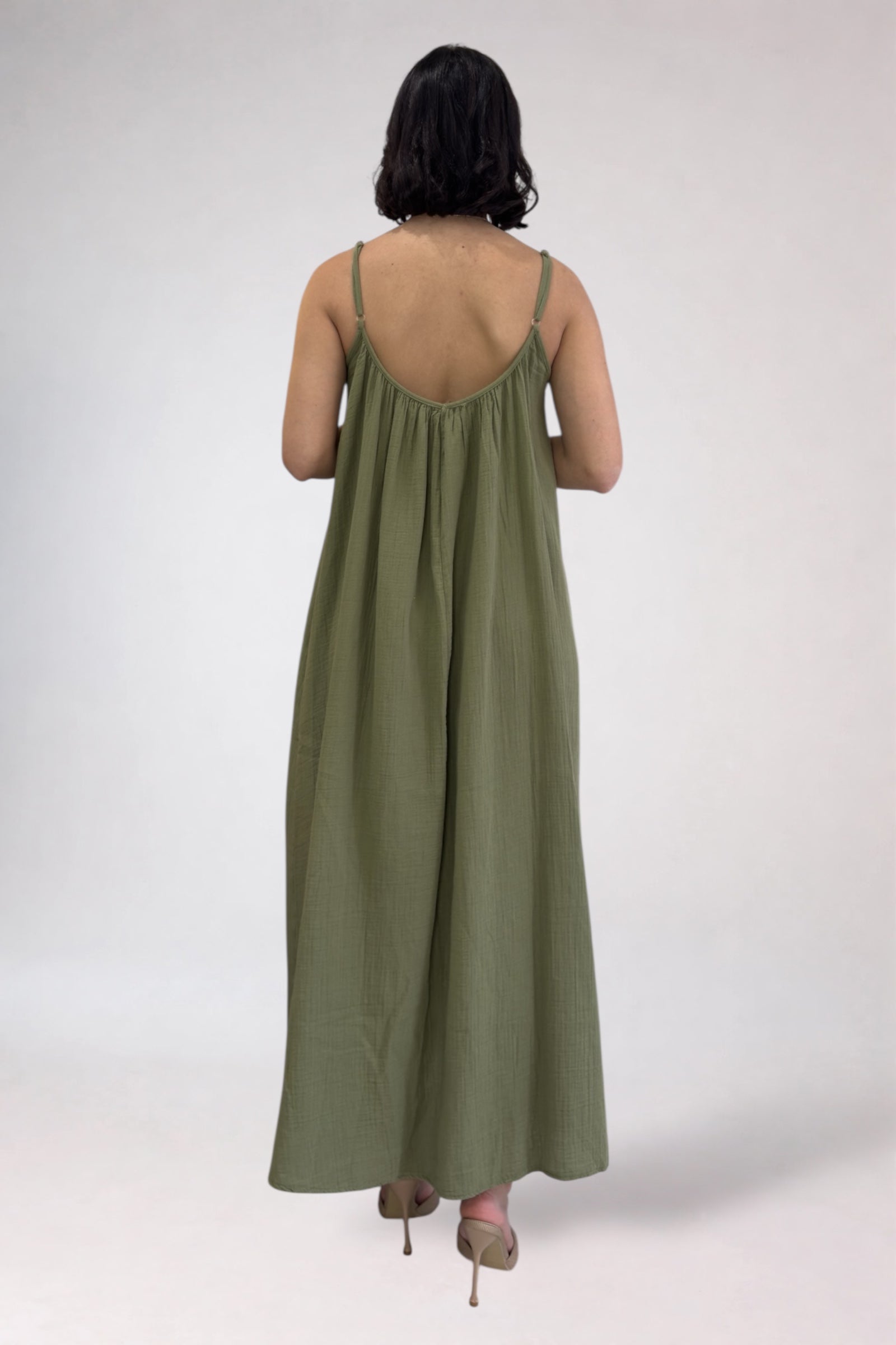 Person wearing a green dress with thin straps on a white background