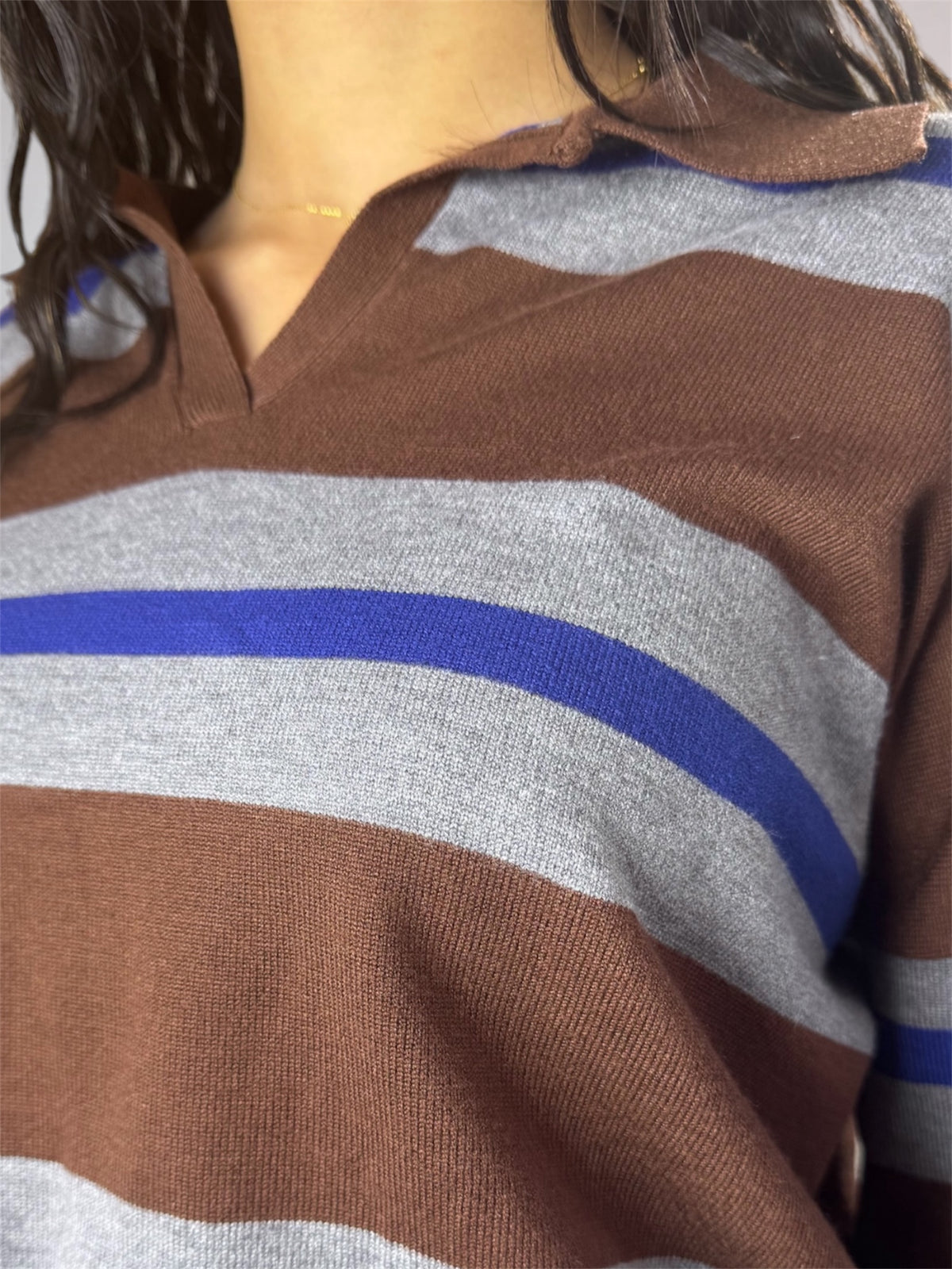 Close-up of a striped knit top with horizontal brown, light gray, and blue stripes, worn by a model.