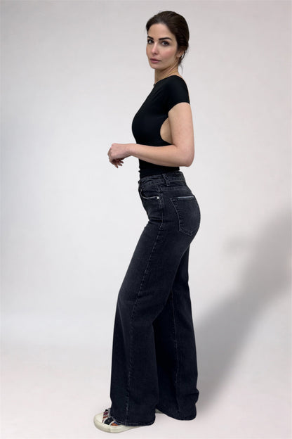 Woman wearing black high-waisted jeans and a black top on a white background