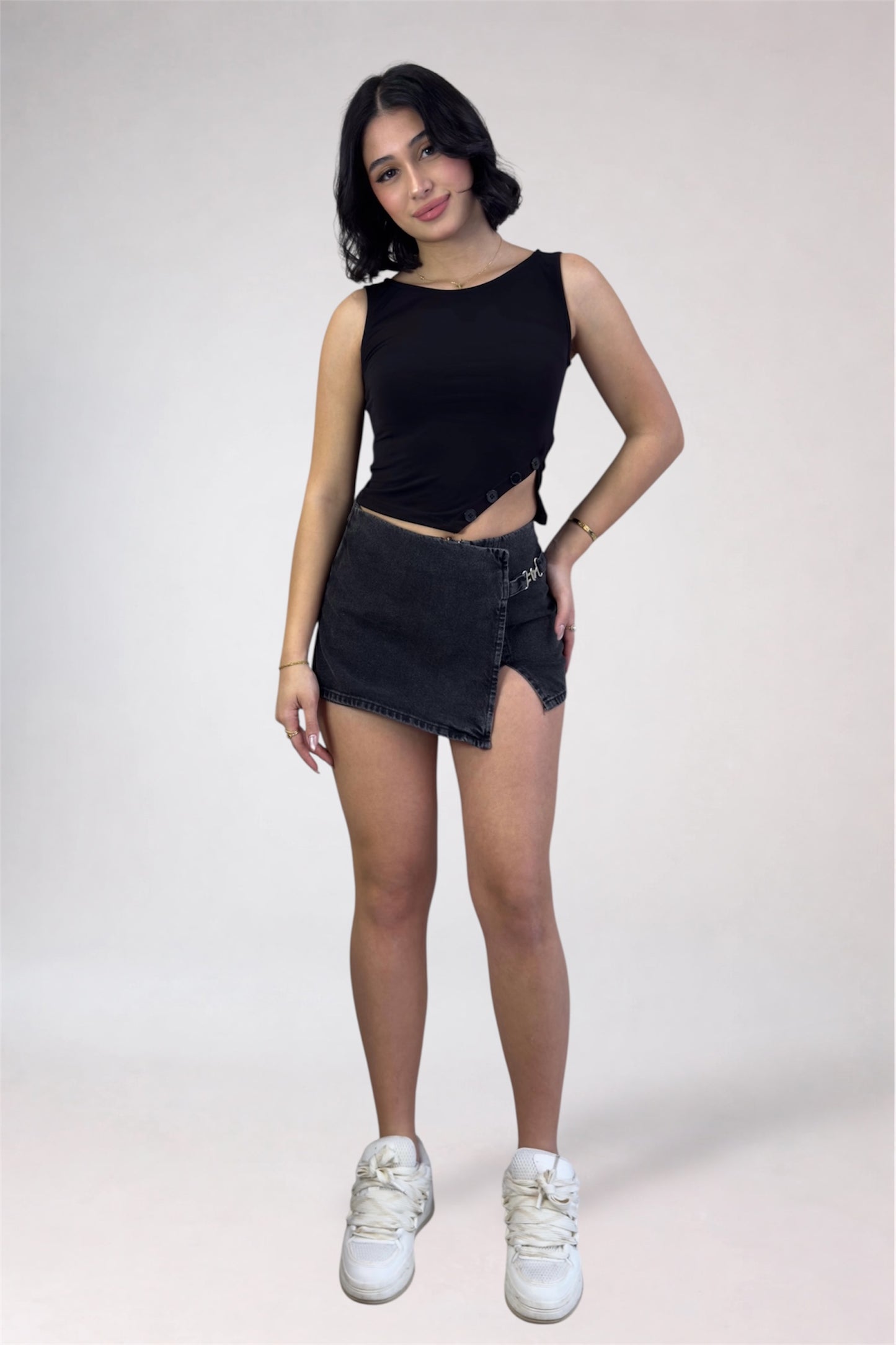 Woman wearing a black sleeveless top and denim shorts on a white background