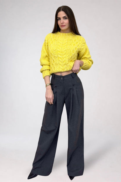 Woman wearing a yellow sweater and black pants on a white background