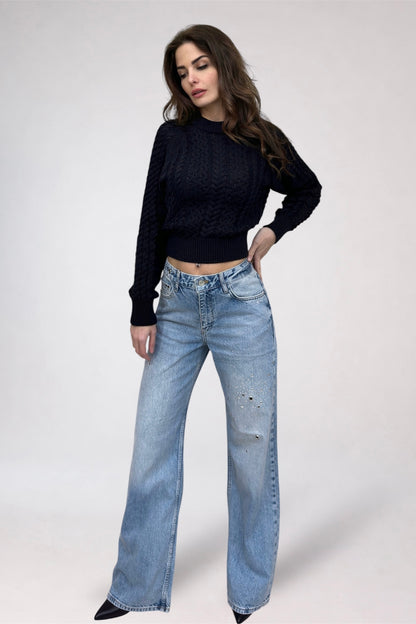 Woman wearing a black sweater and light blue jeans on a white background