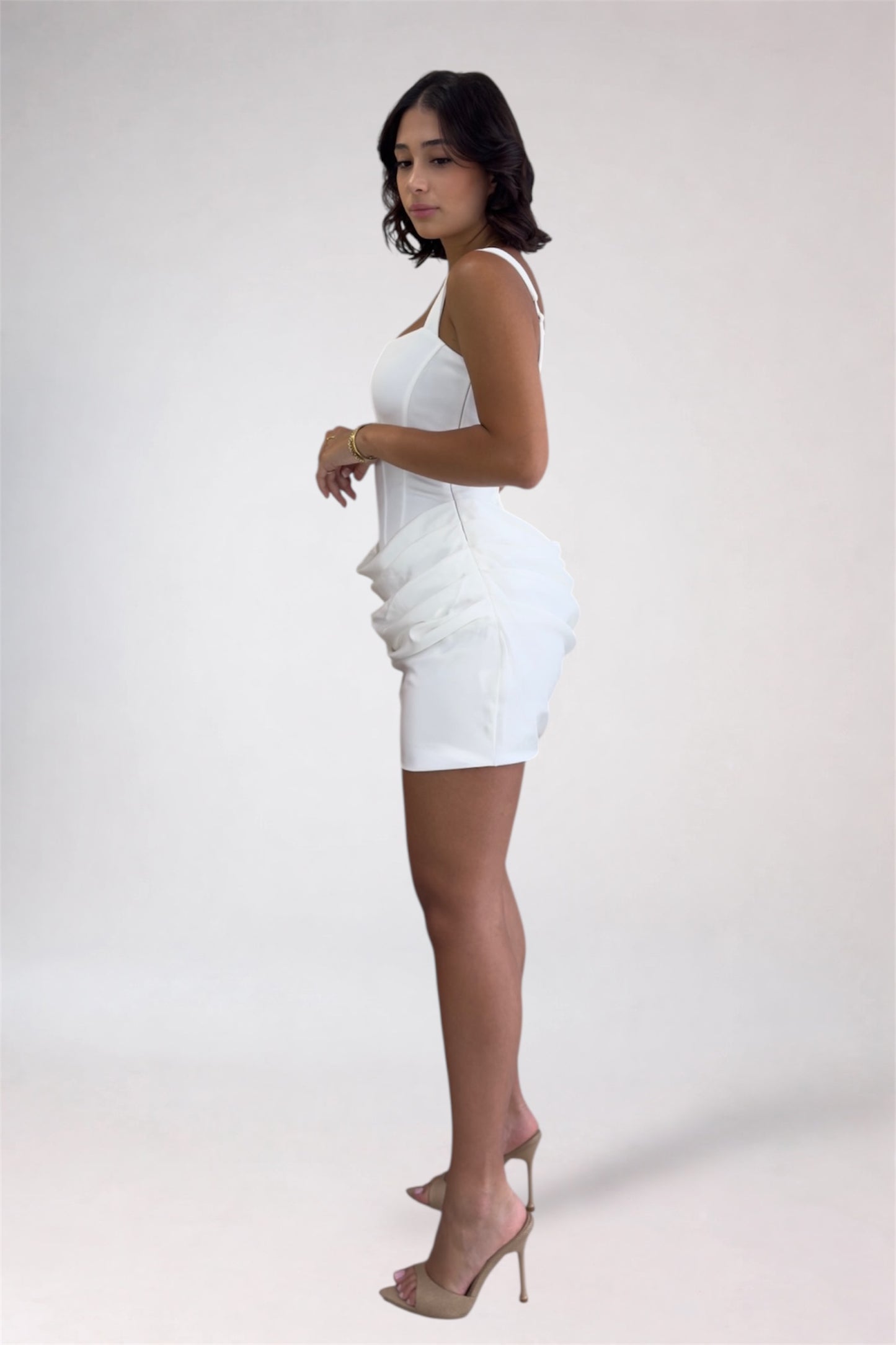 Woman wearing a white dress with ruffled details on a plain background