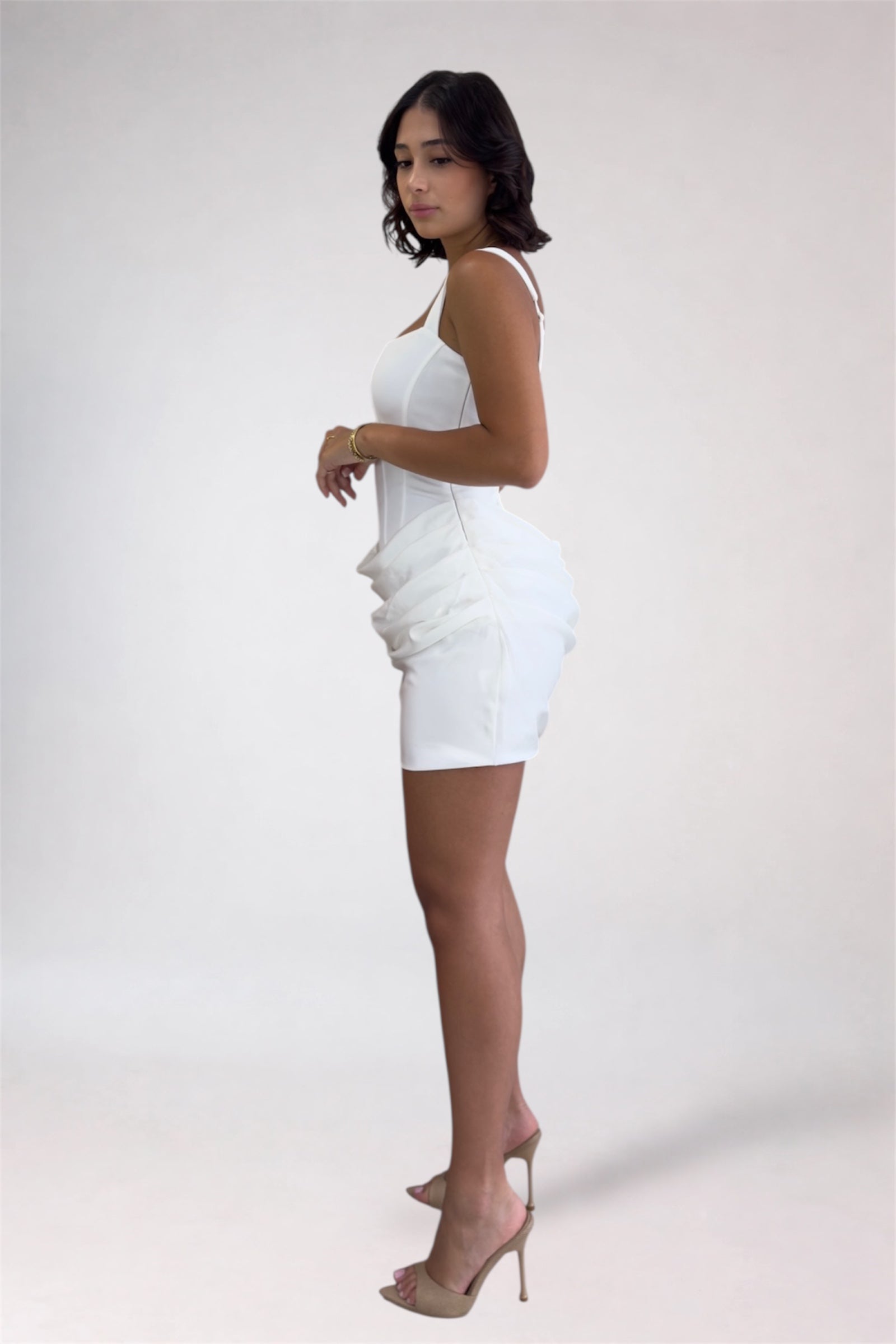 Woman wearing a white dress with ruffled details on a plain background