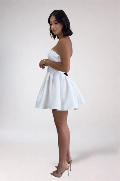 Woman wearing a white strapless dress on a plain background