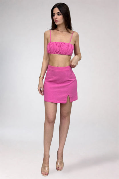 Woman wearing a pink two-piece outfit on a white background