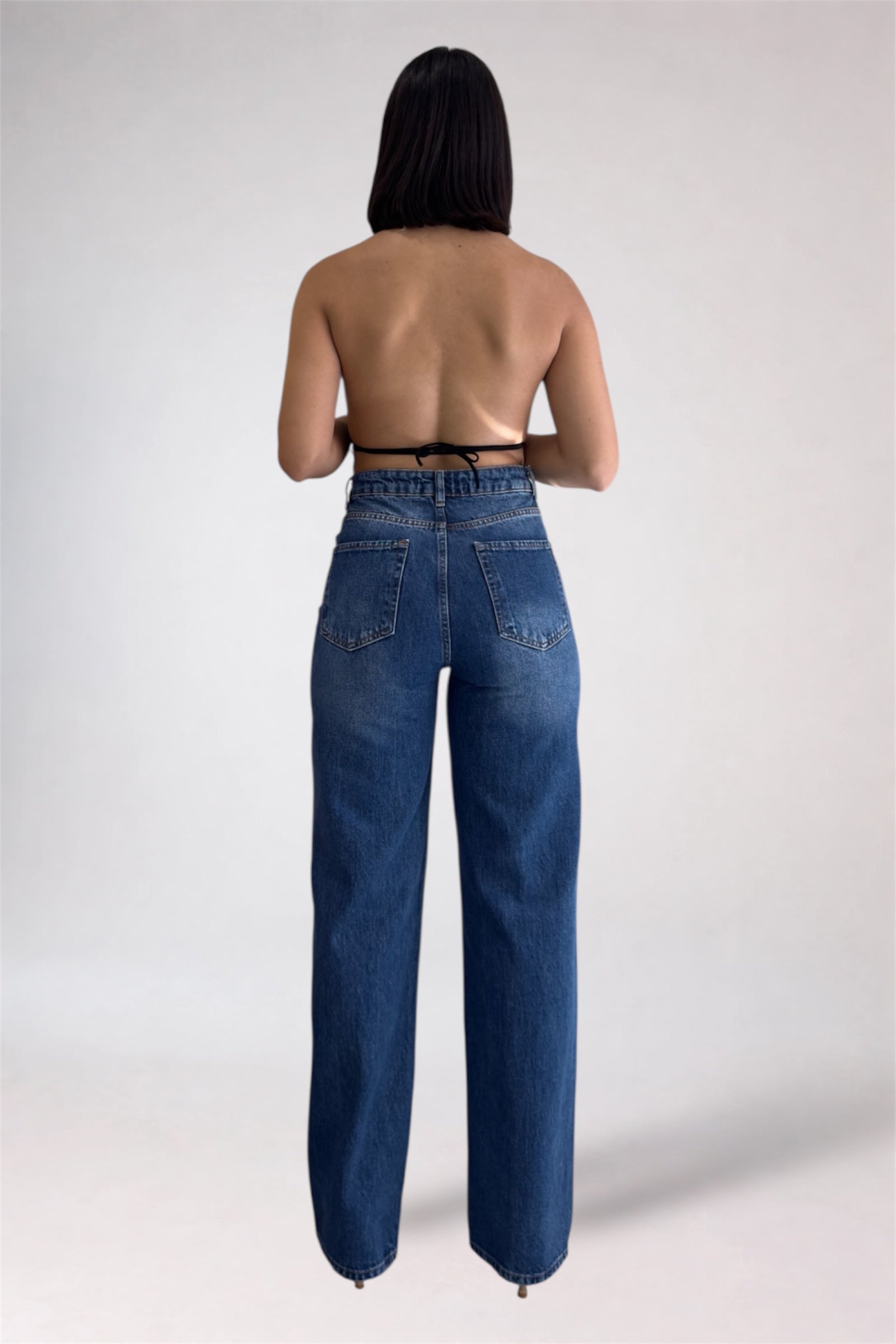 Person wearing blue jeans on a plain background