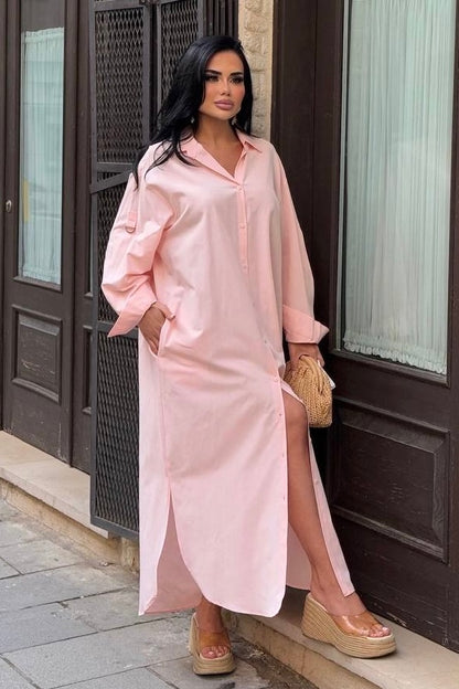 Woman wearing a pink dress with a slit standing outside a building.