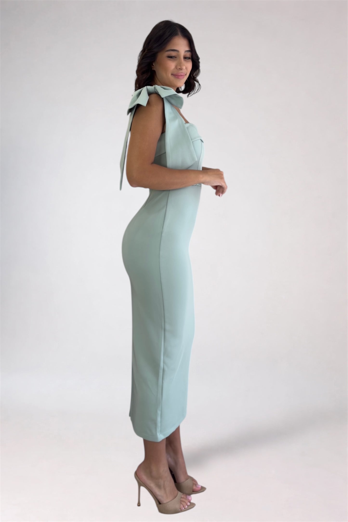 Woman wearing a light blue dress with bow details on a white background