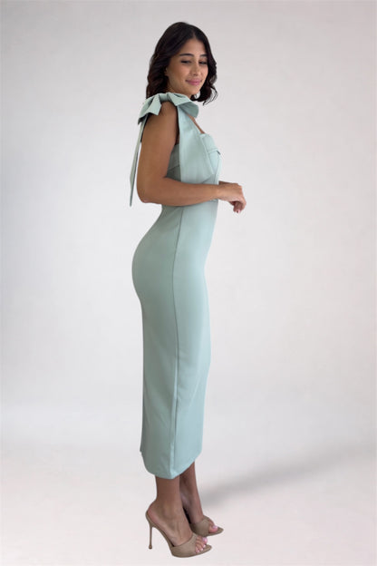 Woman wearing a light blue dress with bow details on a white background
