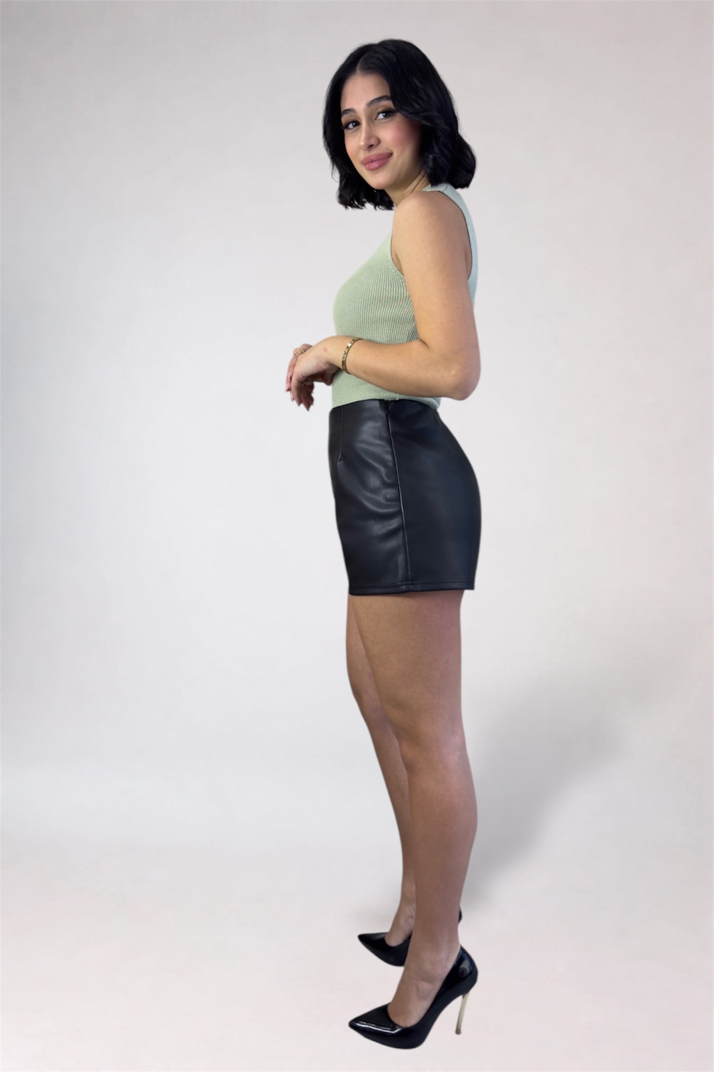 Woman wearing a green top and black leather skirt on a white background