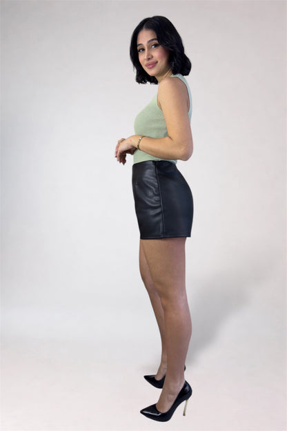 Woman wearing a green top and black leather skirt on a white background