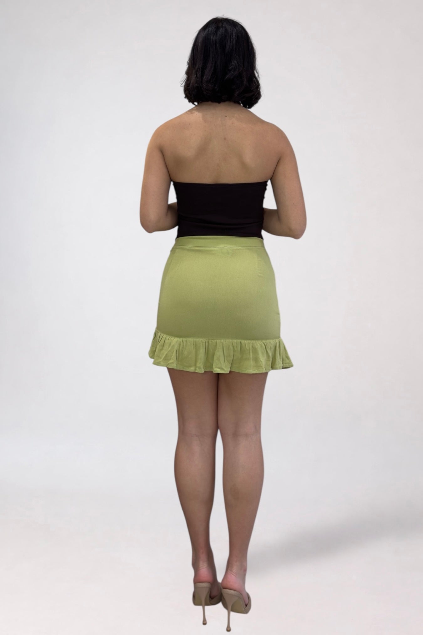 Person wearing a black top and green skirt on a white background