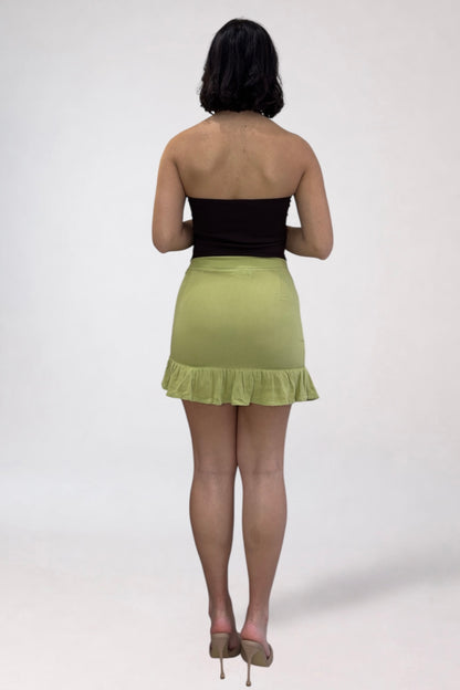 Person wearing a black top and green skirt on a white background