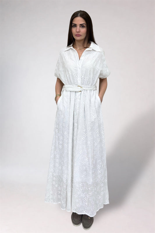 Woman wearing a white dress with a belt on a plain background