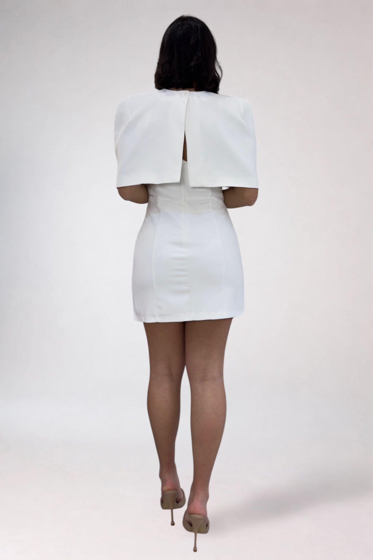 Person wearing a white dress with a matching cape on a white background
