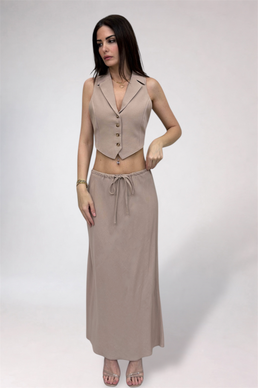 Woman wearing a beige vest and long skirt on a white background