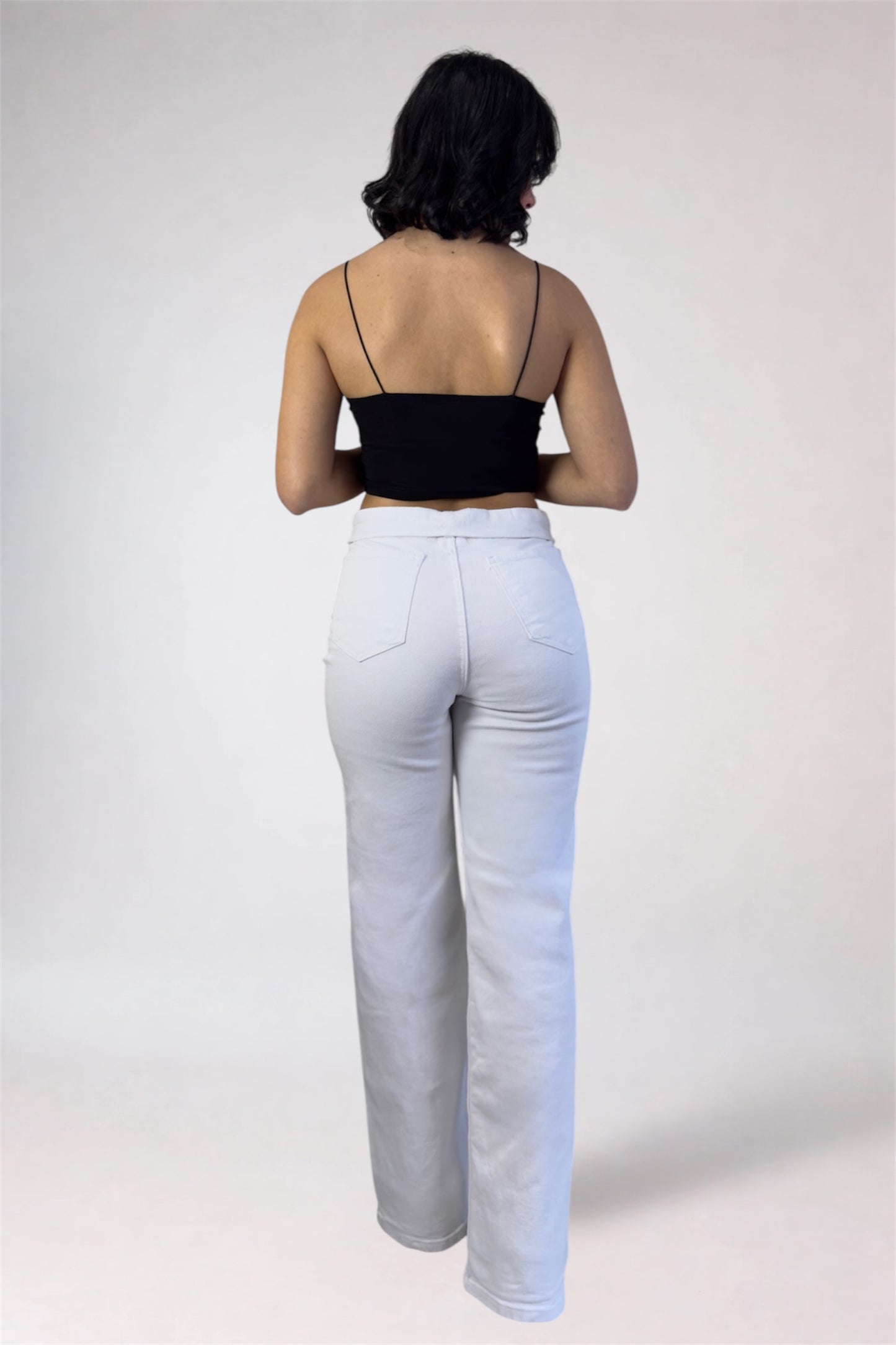 Person wearing a black top and white pants on a plain background