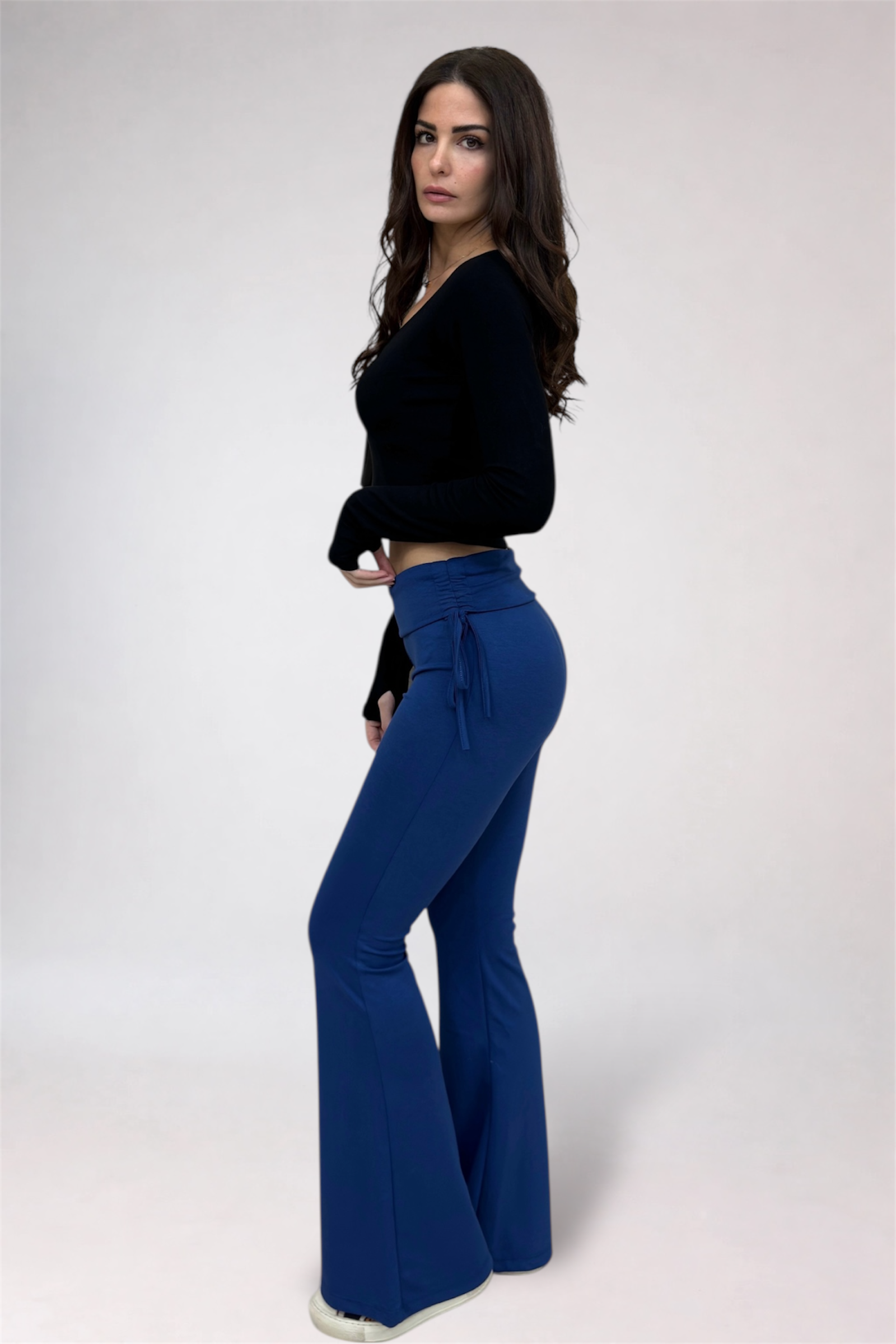Woman wearing a black top and blue flared pants on a white background