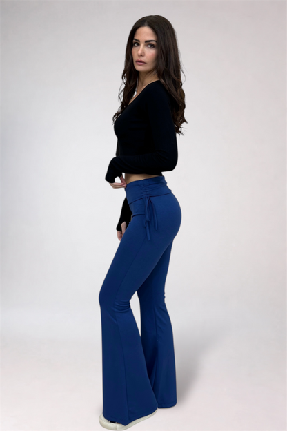 Woman wearing a black top and blue flared pants on a white background