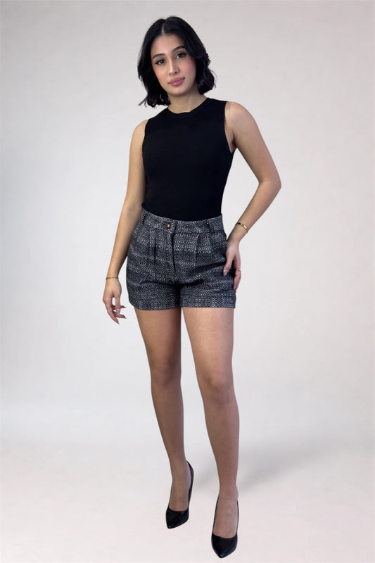 Woman wearing a black sleeveless top and patterned shorts on a white background