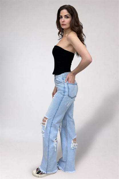 Woman wearing a black top and light blue ripped jeans on a white background